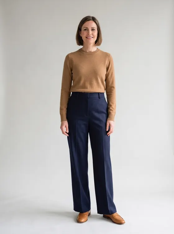 The same woman in the same navy trousers, now wearing a camel fine-knit crewneck sweater